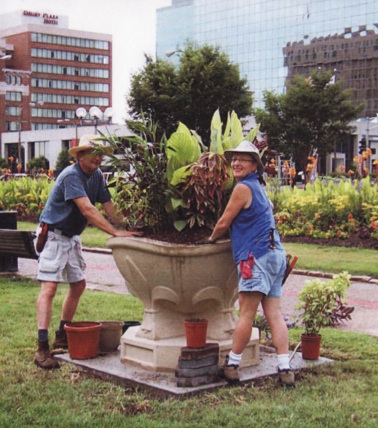 man and woman work to fill planter with flowers and plants