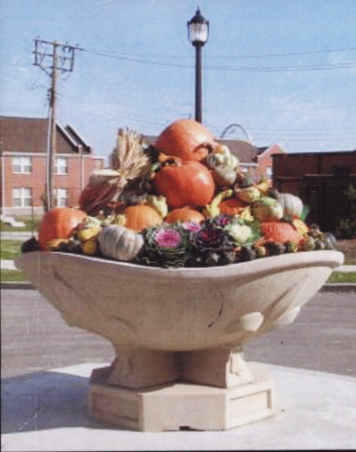 large planter full of fall-related decorations, such as pumpkins